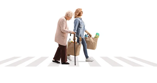 高齢の女性が通りを横断し 白い背景に隔離された食料品袋を運ぶ — ストック写真