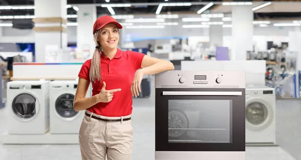 Vrouwelijke Winkelbediende Wijst Naar Een Elektrische Oven Een Winkel — Stockfoto