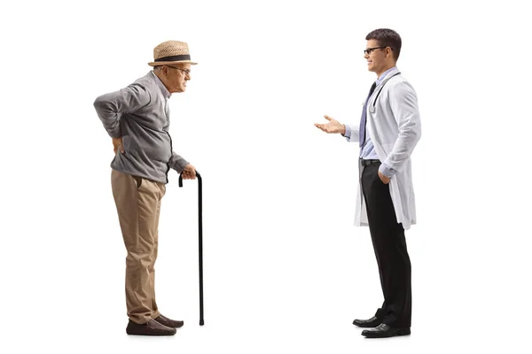背中を痛めて白い背景に隔離された男性医師と話している老人の完全な長さのプロフィールショット — ストック写真
