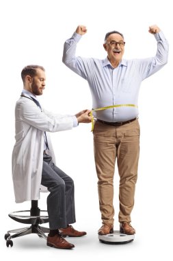 Ağırlık ölçeğinde duran olgun bir adam ve beyaz arka planda izole edilmiş belini ölçen doktor.