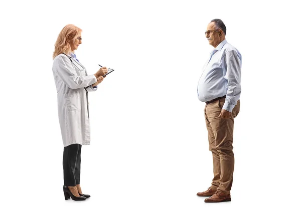 白い背景に隔離された成熟した男と文書を書き 立っている女性医師の完全な長さのプロフィールショット — ストック写真