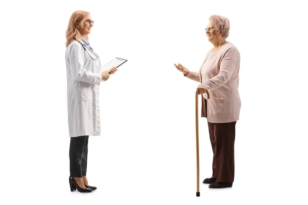 白地に隔離された女性医師と話す高齢女性の完全長プロファイルショット — ストック写真