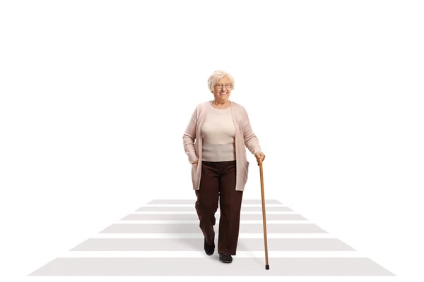 在白色背景隔离的人行横道上行走的一位拿着手杖的老年妇女的全长肖像 — 图库照片