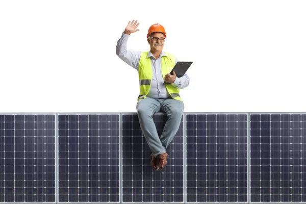 Reifer Männlicher Ingenieur Sitzt Auf Einem Solarpanel Und Winkt Isoliert — Stockfoto