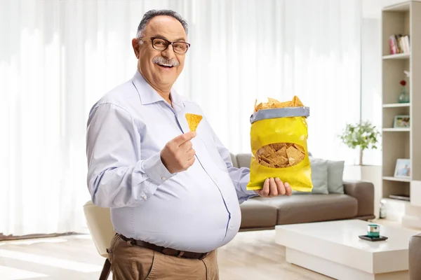 Radosny Dojrzały Mężczyzna Chipsy Tortilla Uśmiecha Się Domu — Zdjęcie stockowe