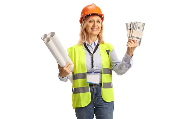 快乐的女工程师 穿着安全背心 头戴安全帽 手里拿着一堆堆白色背景的钱 — 图库照片