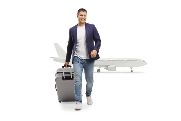 白い背景に孤立した飛行機の前で 男の笑顔とスーツケースを引くの完全な長さの肖像画 — ストック写真