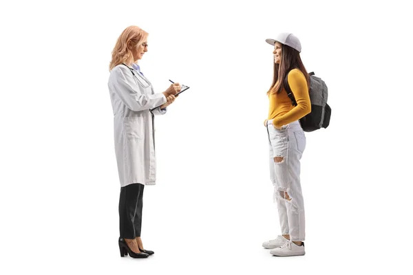 白い背景に隔離された文書を書いている女性医師に立って話をする女性学生の完全な長さのプロフィールショット — ストック写真