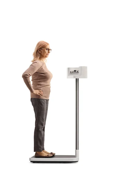 白い背景に隔離されたプロの医療規模で彼女の体重をチェックする女性のフル長さのプロフィールショット — ストック写真