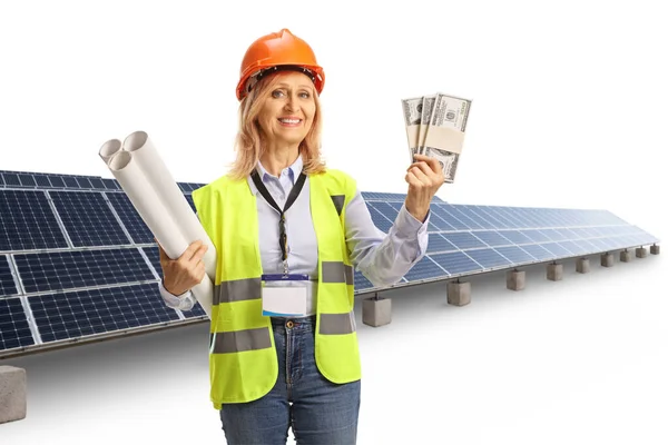 白い背景に隔離された太陽光発電所でお金のスタックを保持する女性エンジニア — ストック写真