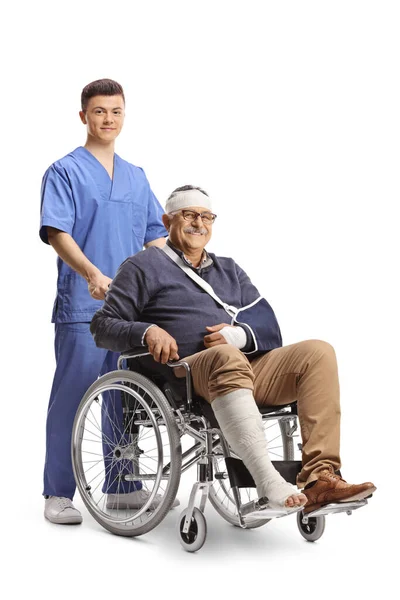 白い背景に隔離された車椅子に座っている頭の上に腕と包帯が壊れている成熟した男と医療従事者 — ストック写真