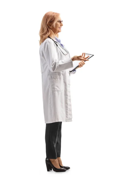 クリップボードを持っている女性医師の完全な長さのプロフィールショットと白の背景に孤立した手で何かを説明 — ストック写真