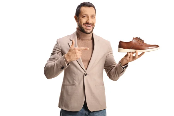 若い男は茶色の革の靴を保持し 白い背景に隔離された指す — ストック写真