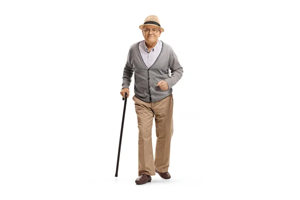 一个拿着手杖走向被白色背景隔离的相机的老年男子的全长肖像 — 图库照片