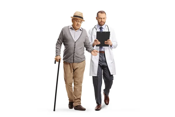 一个拿着手杖走路的老年男子的全长画像 并与一位因白人背景而被隔离的年轻男医生交谈 — 图库照片
