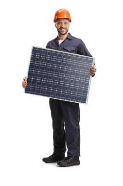 Üniformalı bir fabrika işçisi beyaz arka planda güneş paneli tutuyor.