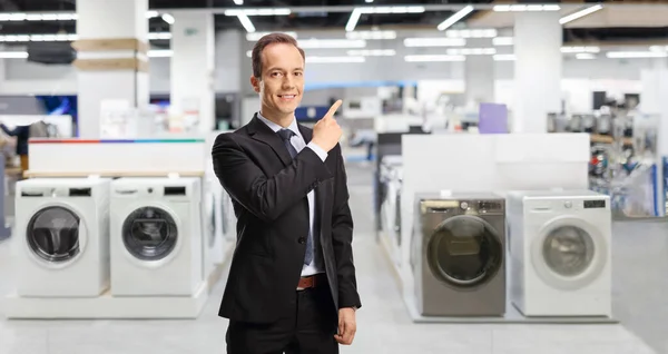 Businessman pointing at an appliance shop with washing machines