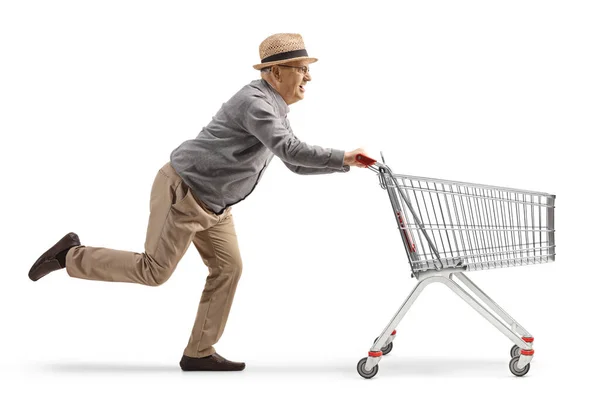 白い背景に空っぽのショッピングカートで走っている高齢者の完全な長さのショット — ストック写真