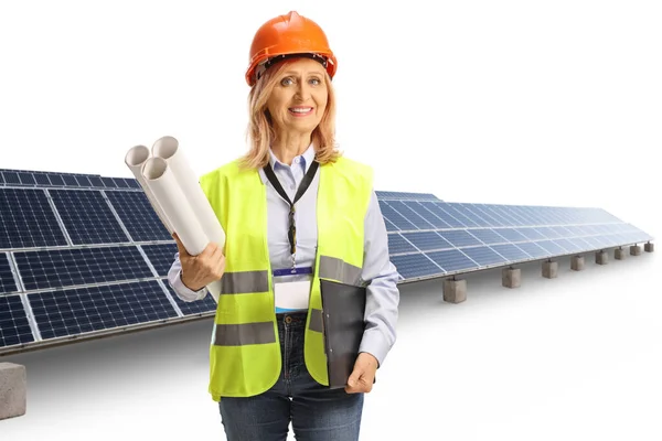 安全ベストとハード帽子を保持している女性エンジニア設計図と白い背景に隔離された太陽電池パネルの前のクリップボード — ストック写真