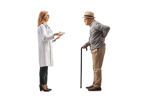 背中が痛くて白い背景に隔離された女性医師と話をする高齢者のフル長プロファイルショット — ストック写真