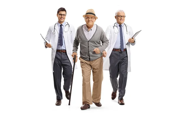 一个拿着手杖的老年男子和一个身披白色背景的男医生的全长肖像 — 图库照片