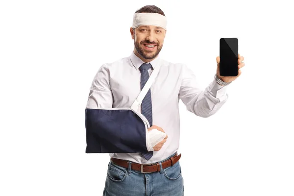 Mladý Muž Zlomenou Rukou Obvazem Hlavě Ukazuje Smartphone Izolované Bílém — Stock fotografie