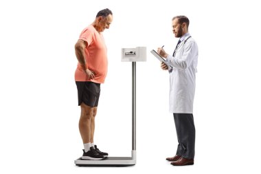 Erkek doktor, beyaz arka planda izole edilmiş ağırlık ölçeğinde duran olgun bir adamın ağırlığını kontrol ediyor.