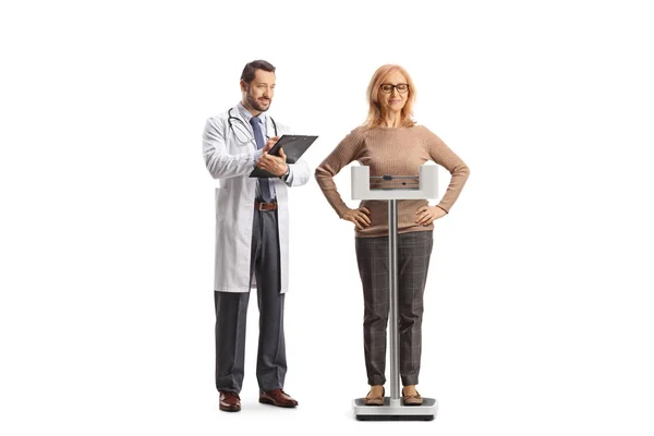 白地に隔離された体重計の上に立つ医師と熟女 — ストック写真