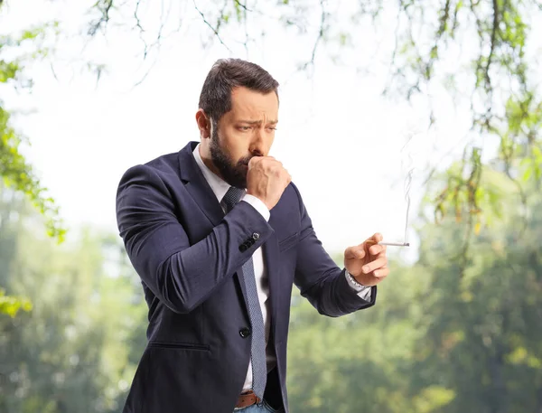公園の外で煙草を吸って咳をする男 — ストック写真