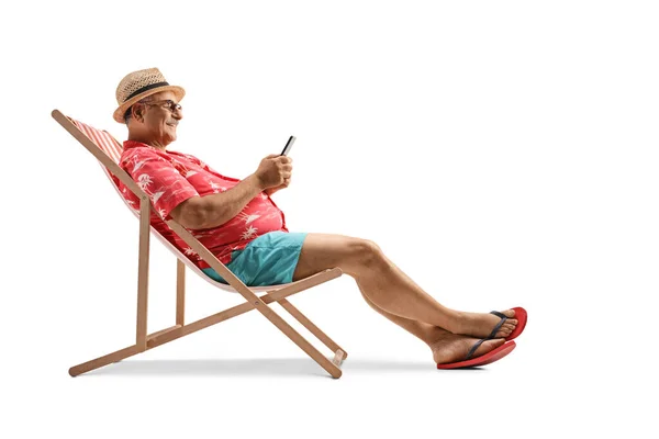 成熟的男性游客坐在沙滩椅子上 手持智能手机 背景是白色的 — 图库照片