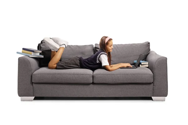 ソファに寝そべって白い背景に隔離されたノートパソコンを使う女子高生 — ストック写真