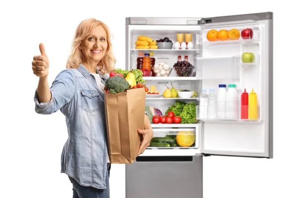 Зрелая Женщина Улыбающейся Сумкой Показывающей Большой Палец Вверх Перед Холодильником — стоковое фото