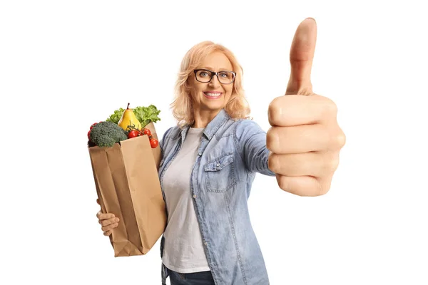 袋の笑顔と白い背景に隔離された親指アップサインを示す食料品の袋を持つ熟女 — ストック写真