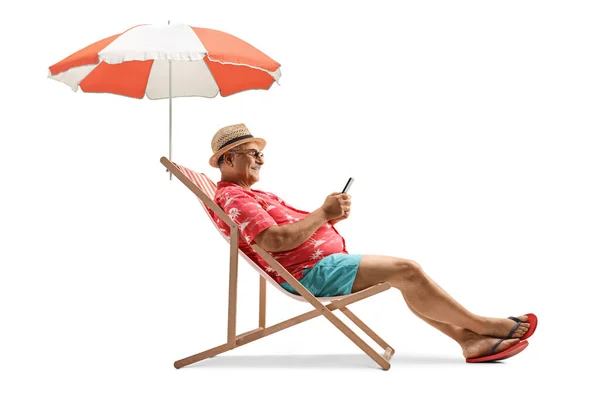 Volwassen Man Zittend Een Strandstoel Onder Paraplu Met Een Smartphone — Stockfoto