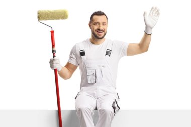 Beyaz arka planda izole edilmiş boş bir panele sarılı boya silindirli bir ressam.