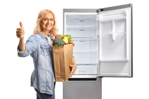 Зрелая Женщина Пакетом Продуктов Перед Холодильником Показывает Большой Палец Вверх — стоковое фото