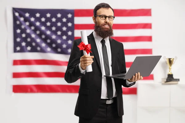 Amerikan Bayrağının Önünde Elinde Diploma Dizüstü Bilgisayar Tutan Takım Elbiseli — Stok fotoğraf