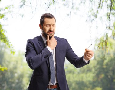 Parkta sigara tutan şüpheli bir adam.