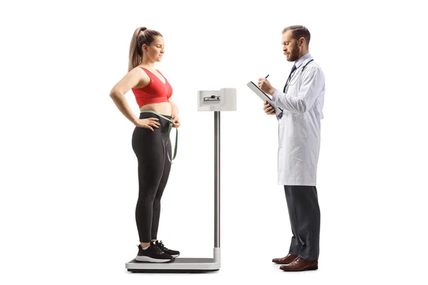 白い背景に隔離された体重計に若い女性の医者の書き方の重み — ストック写真