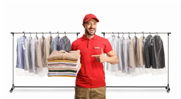 男人拿着一堆叠好的衣服 指着被白色背衬隔开的干洗店 — 图库照片