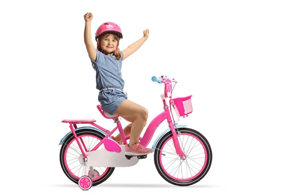 トレーニングホイールとピンクの自転車に乗ってヘルメットを持つ子供と白の背景に隔離された幸福をジェスチャー — ストック写真