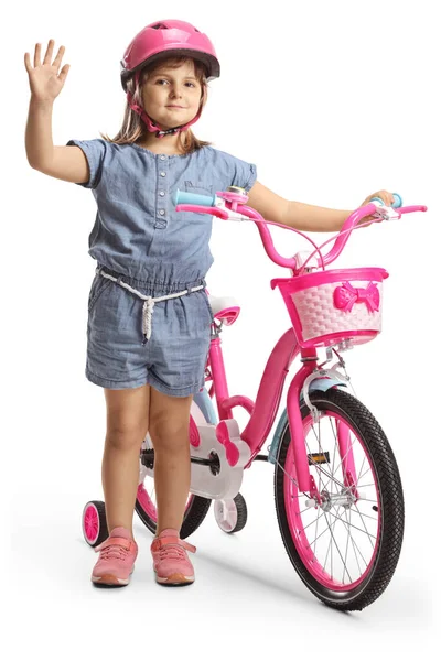ヘルメットをかぶった女の子が自転車の横に立って白い背景に隔離された手を振って — ストック写真