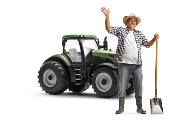 Mature Farmer Shovel Standing Next Green Tractor Waving Isolated White — Stock Photo, Image