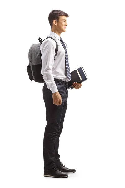 一名身穿校服 手持白色背景书籍的男生的全长侧面照片 — 图库照片