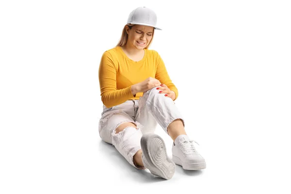 年轻的女性坐在地板上 用白色的背衬抱着疼痛的膝盖 — 图库照片