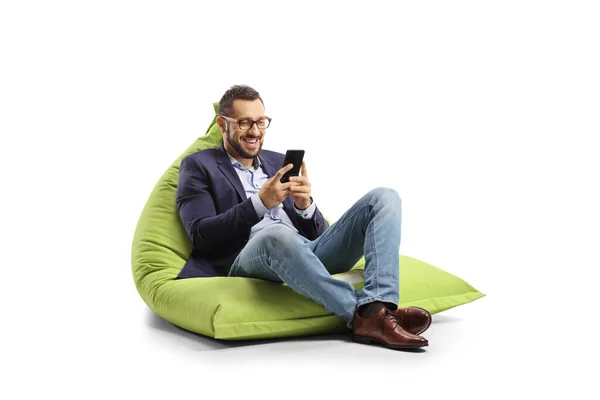 Joven Profesional Sentado Una Bolsa Frijoles Sonriendo Mirando Smartphone Aislado — Foto de Stock