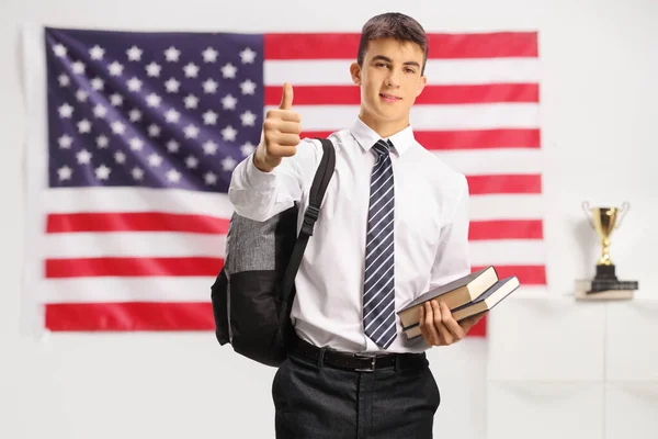 十代の男性学生保持本と親指を米国の旗の前に表示 — ストック写真