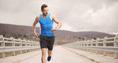 Köprüde koşan ve akıllı bakışlarına bakan bir adam 