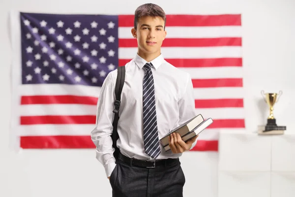 シャツとネクタイを着た男性学生が本を持ち アメリカ国旗の前に立っている — ストック写真