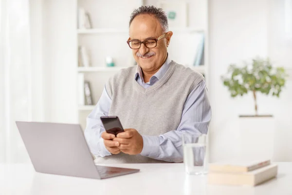 Starší Muž Sedí Stolem Notebookem Pomocí Smartphonu Hom — Stock fotografie